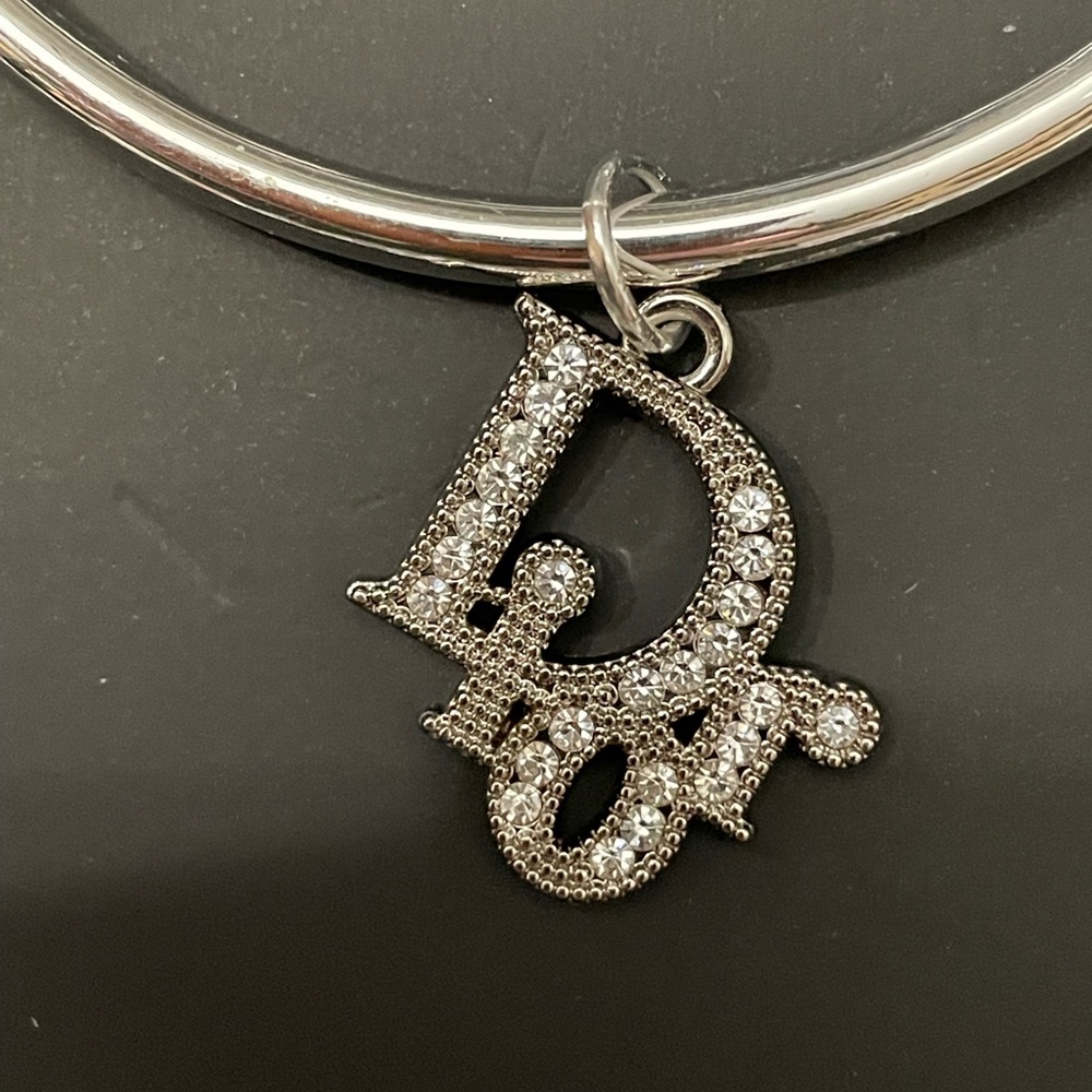 BEAUTIFUL DESIGNER CRYSTAL LOGO PULL CHARM ON NWOT SILVER TONE BANGLE BRACELET